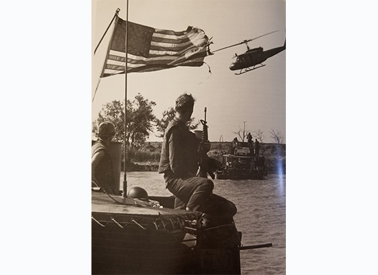 US Navy sailor looking at flag with helicopter flying by