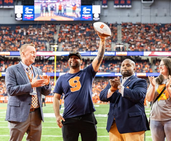 Varun as hometown hero holding a football in the dome.