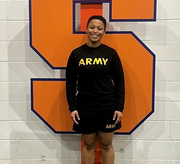 Mariah Carter in her PT gear standing in front of a giant S for SU.